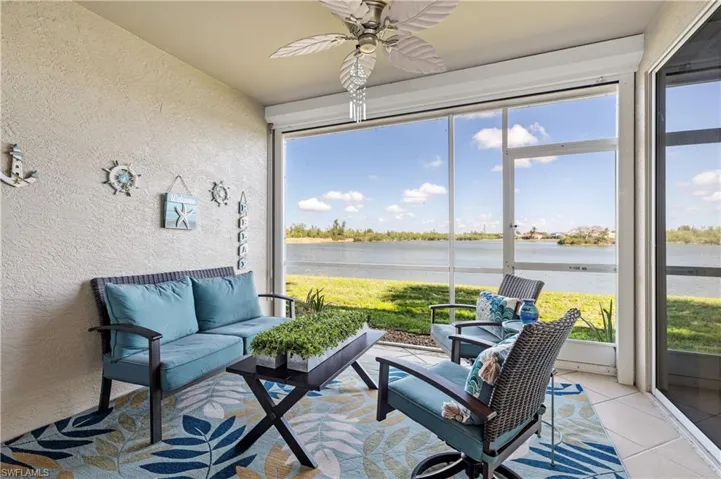 Sunroom / solarium with a textured wall, a ceiling fan, an outdoor lounge area, a water view, and tile patterned flooring