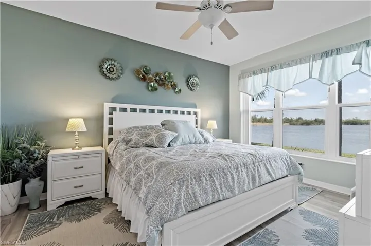 Bedroom with light wood-style floors, ceiling fan, and a water view