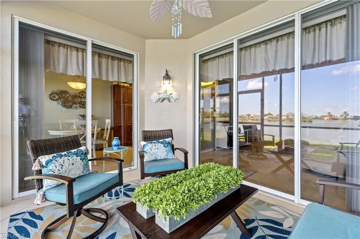 Sunroom with a ceiling fan and a water view