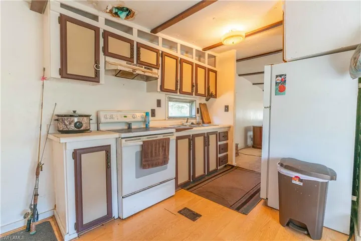 Kitchen featuring light hardwood / wood-style flooring, white appliances, and sink