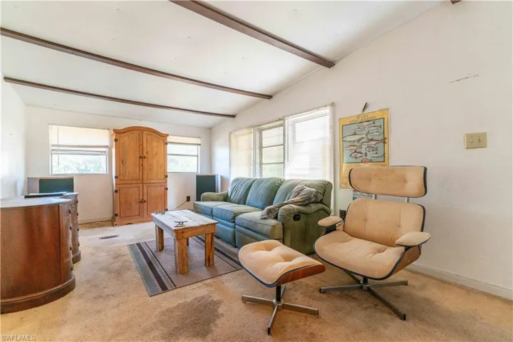 Carpeted living room with lofted ceiling with beams