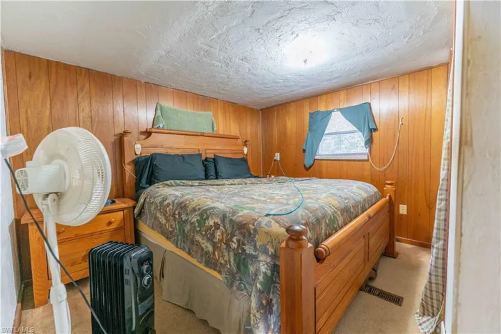 Bedroom featuring wooden walls and light colored carpet