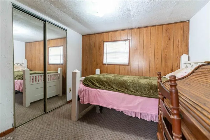 Bedroom with carpet flooring, wood walls, a closet, and a textured ceiling