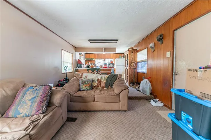 Carpeted living room featuring a textured ceiling, a wealth of natural light, and wood walls