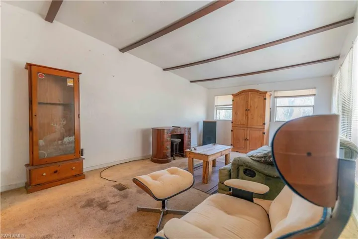 Carpeted living room featuring beamed ceiling