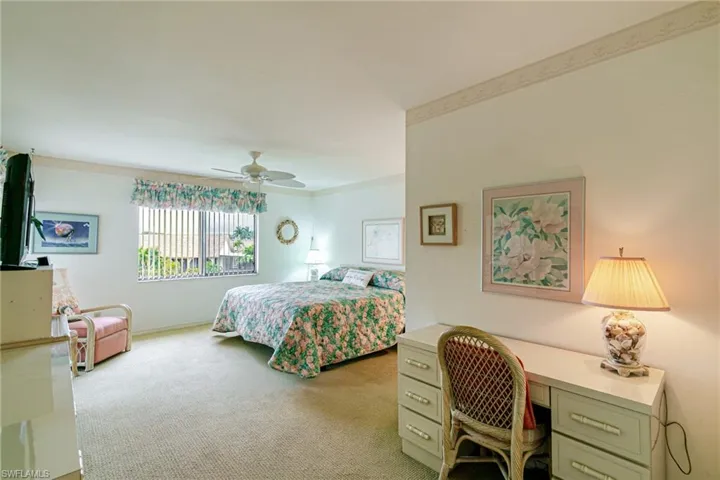 Bedroom with light colored carpet, a ceiling fan, crown molding, and a desk