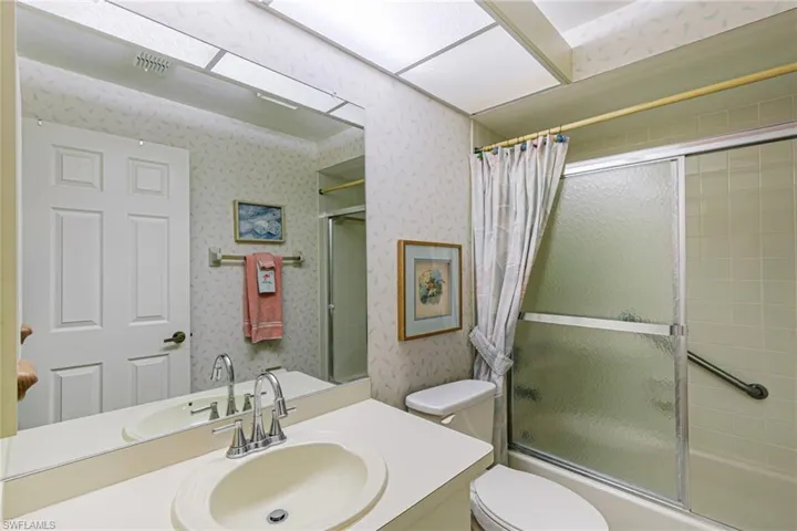 Full bath featuring vanity, wallpapered walls, and bath / shower combo with glass door