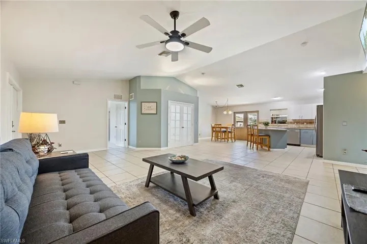 Living area with light tile patterned flooring, ceiling fan, vaulted ceiling, and baseboards