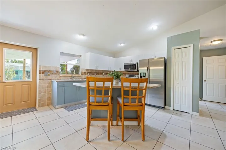 Kitchen featuring stainless steel appliances, light countertops, light tile patterned flooring, lofted ceiling, and tile walls