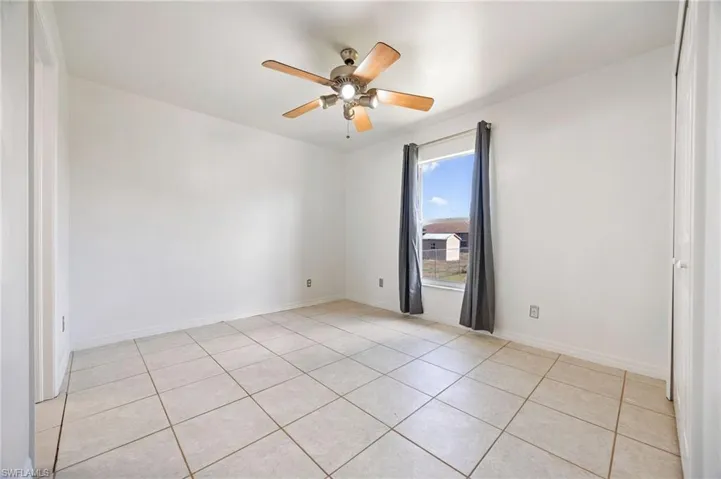 Unfurnished room featuring light tile patterned floors, ceiling fan, and baseboards