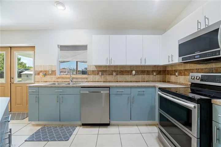 Kitchen with stainless steel appliances, a sink, light countertops, and decorative backsplash