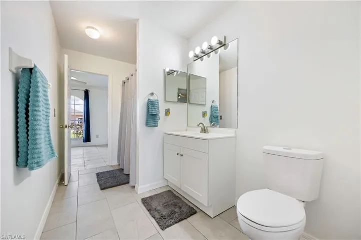Full bath featuring toilet, baseboards, vanity, and tile patterned flooring