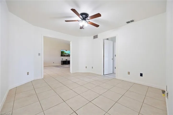 Spare room with ceiling fan, light tile patterned floors, and baseboards