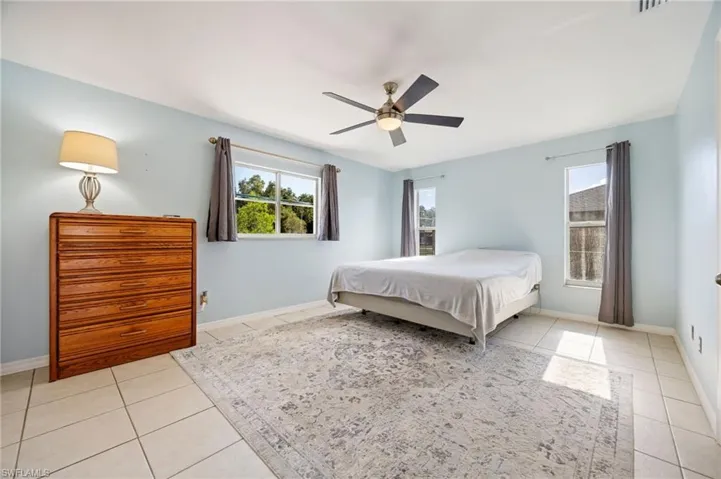 Bedroom with light tile patterned flooring, baseboards, and ceiling fan