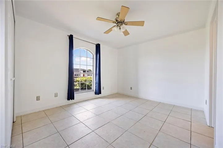 Unfurnished room with ceiling fan, light tile patterned floors, and baseboards