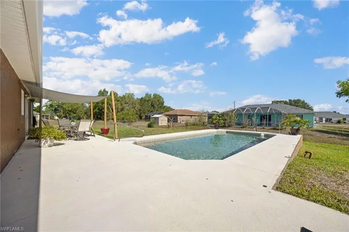 Swimming pool with a patio area, outdoor dining area, and a lawn