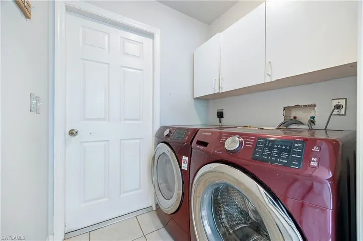 Washroom with washer and clothes dryer, cabinet space, and light tile patterned floors