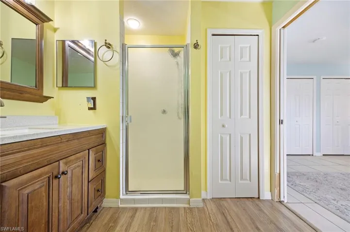 Full bath with a closet, a stall shower, and vanity
