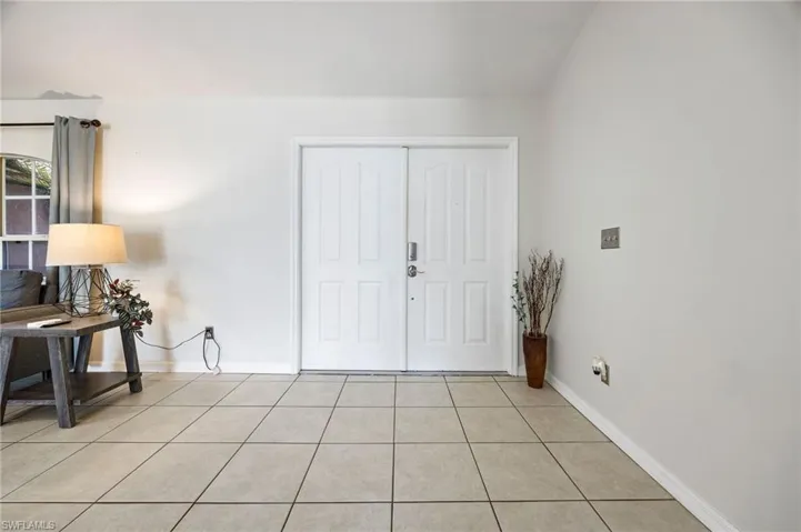 Foyer with light tile patterned floors and baseboards