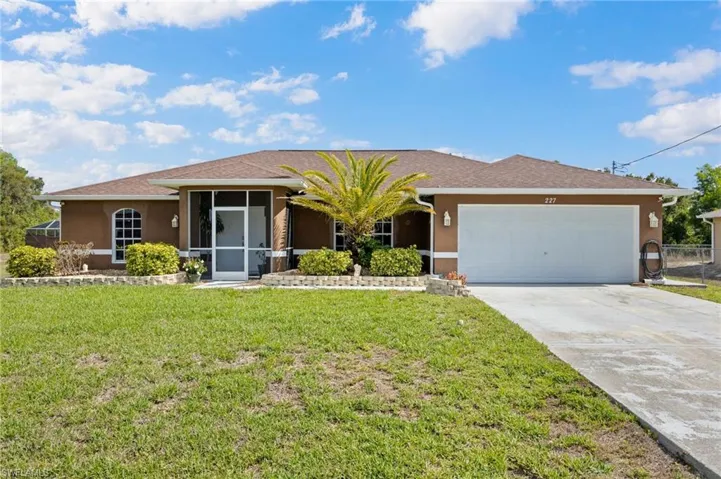 Single story home featuring stucco siding, an attached garage, driveway, and a front yard