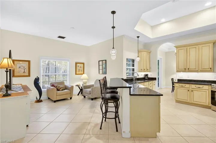 Kitchen featuring light tile patterned floors, open floor plan, cream cabinetry, dark countertops, and a peninsula