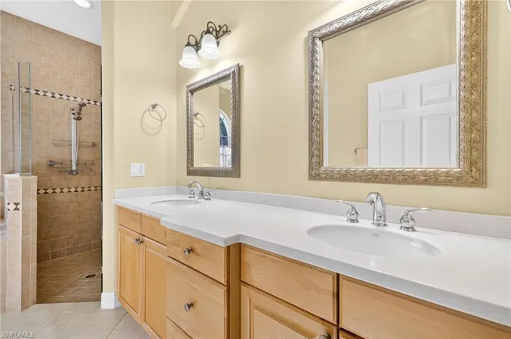 Bathroom with tiled shower, double vanity, tile patterned flooring, and recessed lighting
