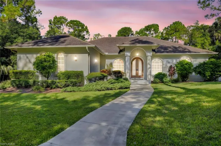 View of front of property with a lawn, stucco siding, a shingled roof, and french doors