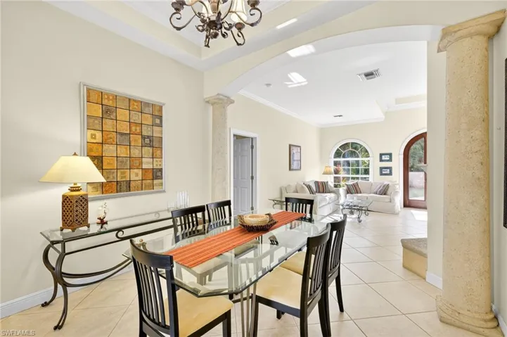 Dining room featuring arched walkways, decorative columns, crown molding, and light tile patterned flooring