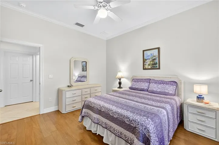 Bedroom featuring wood finished floors, crown molding, and ceiling fan