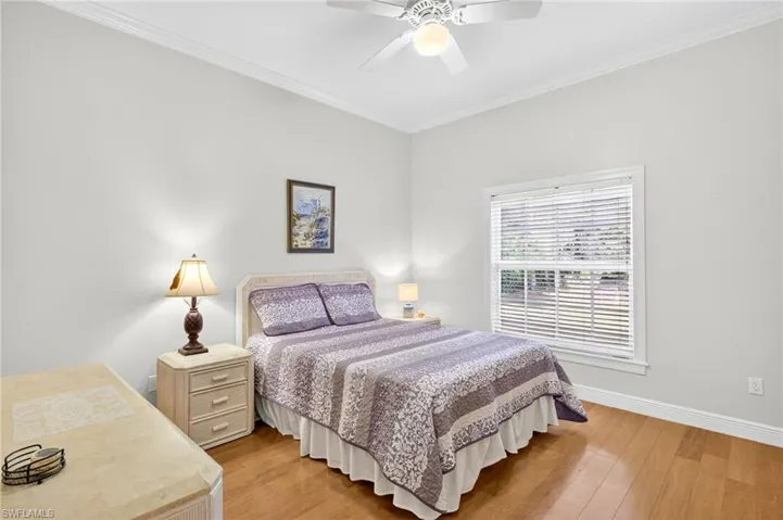 Bedroom featuring ornamental molding, light wood-style floors, and a ceiling fan