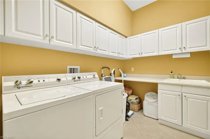 Laundry room with separate washer and dryer, cabinet space, and light tile patterned flooring