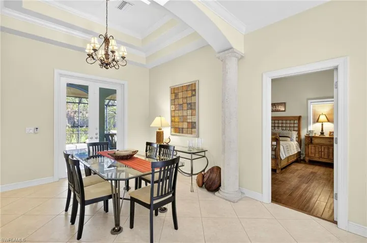 Dining area with ornamental molding, decorative columns, arched walkways, french doors, and a tray ceiling