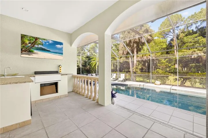 Outdoor pool featuring a patio area, glass enclosure, and a grill