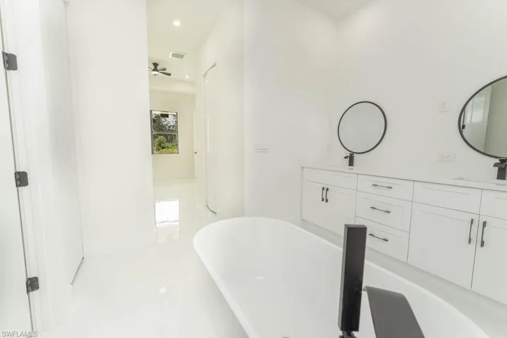 Bathroom with a freestanding tub, double vanity, and recessed lighting