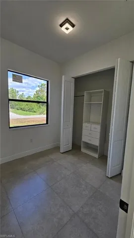 Unfurnished bedroom with baseboards, tile patterned flooring, and a closet