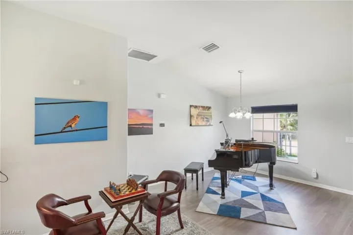 Sitting room with lofted ceiling, light wood-style flooring, and hanging lights