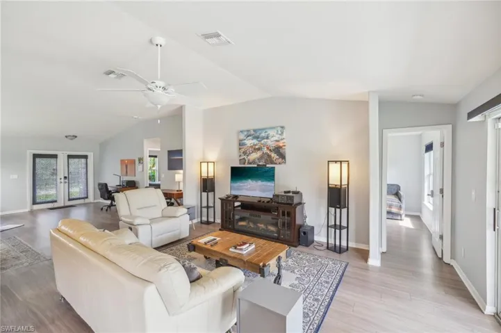 Living area featuring wood finished floors, french doors, a ceiling fan, and an office area