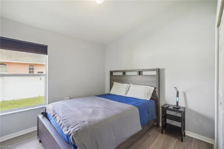 Bedroom with wood finished floors and lofted ceiling