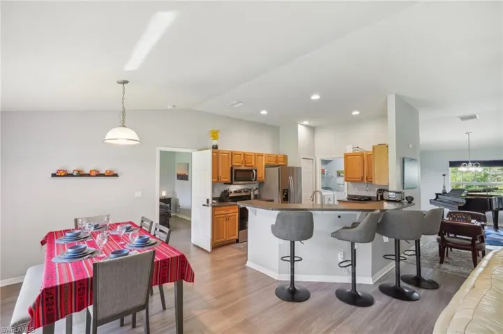 Kitchen featuring pendant lighting, a kitchen breakfast bar, a peninsula, light wood-style floors, and vaulted ceiling