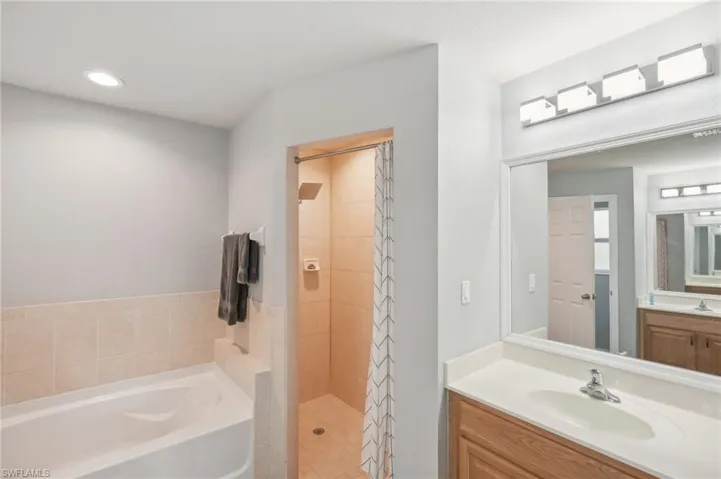 Full bathroom featuring vanity, a stall shower, a bath, and recessed lighting