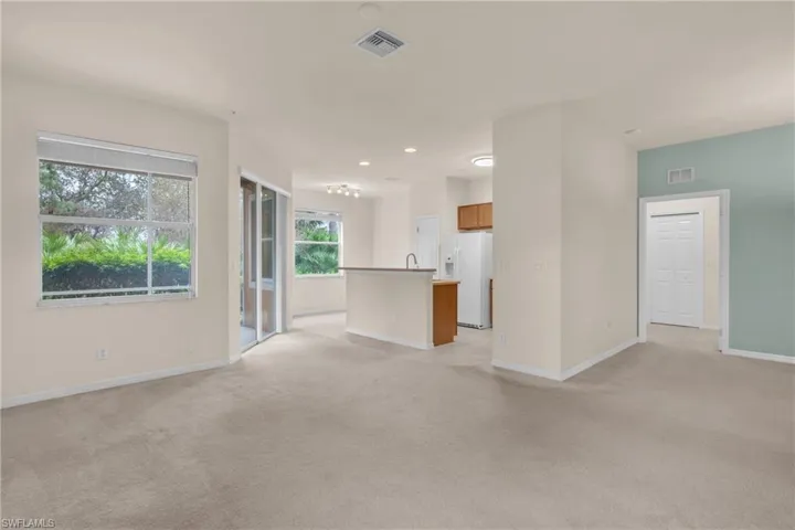 Unfurnished living room featuring light colored carpet and baseboards