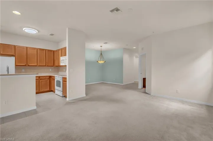 Kitchen with light countertops, decorative light fixtures, white appliances, open floor plan, and recessed lighting