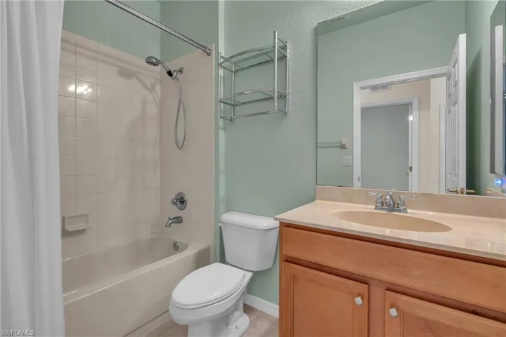 Full bathroom with a textured wall, shower / tub combo, and vanity