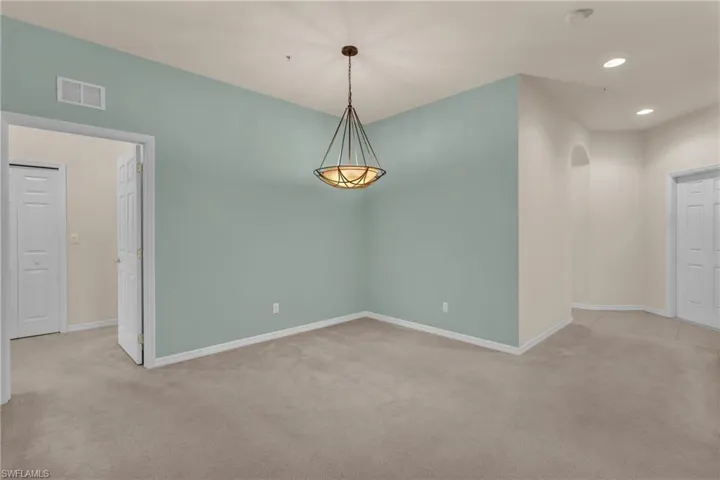 Spare room featuring light carpet, recessed lighting, and arched walkways