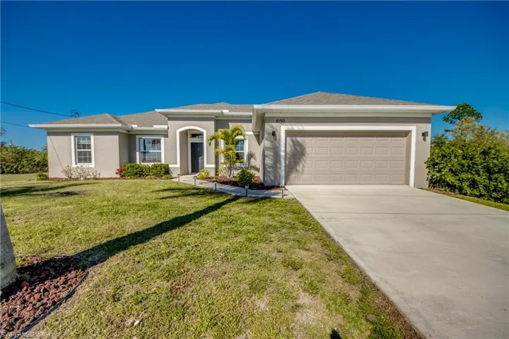 View of front of property featuring stucco siding, an attached garage, driveway, and a front yard