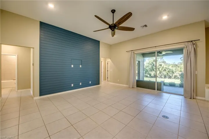 Empty room featuring ceiling fan, light tile patterned flooring, recessed lighting, and an accent wall