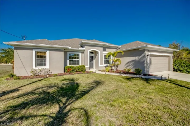 Single story home with a garage, a front yard, stucco siding, and driveway