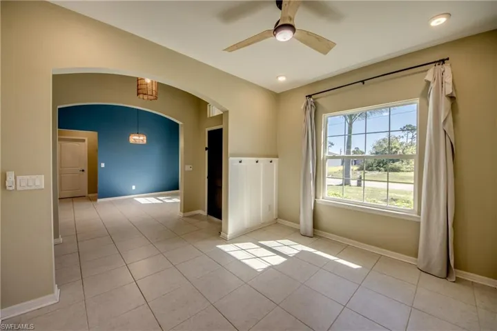 Spare room featuring a ceiling fan, light tile patterned floors, and arched walkways