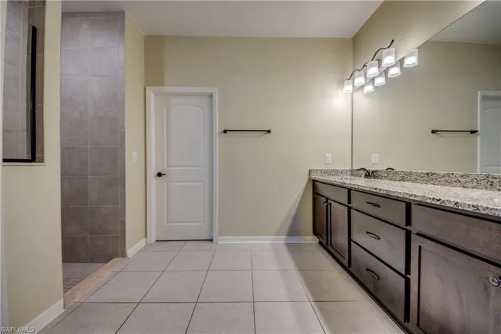 Bathroom featuring vanity, light tile patterned floors, and a walk in shower