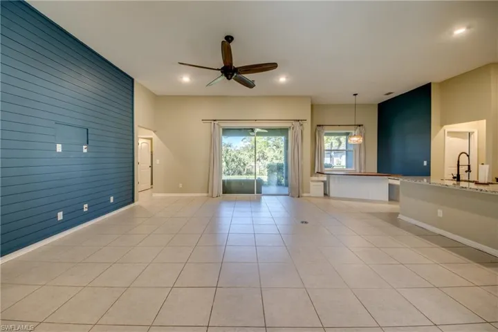 Unfurnished living room with wood walls, ceiling fan, an accent wall, light tile patterned floors, and recessed lighting